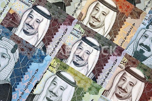 Saudi Arabia riyal money bills banknotes lies in big pile on table close up. Concept of finances and business in Saudi Arabia