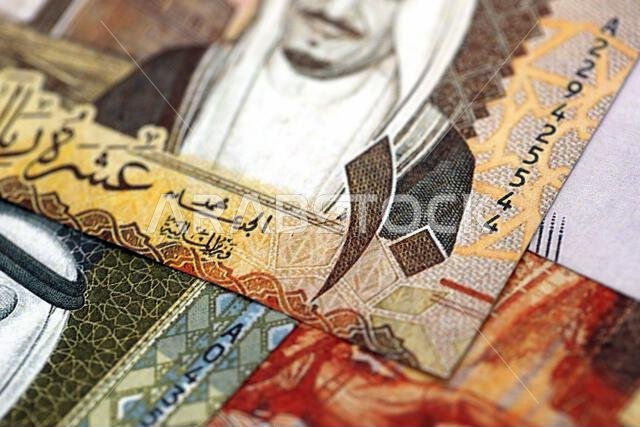 أوراق نقدية من الريال السعودي مكدسة في كومة كبيرة على طاولة، صورة مقرّبة. مفهوم التمويل والأعمال في المملكة العربية السعودية