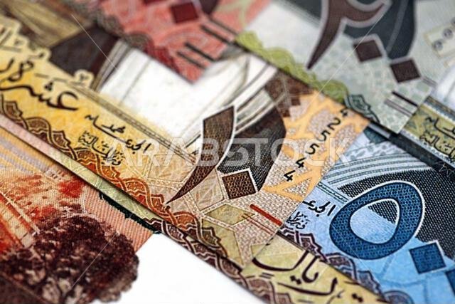 أوراق نقدية من الريال السعودي مكدسة في كومة كبيرة على طاولة، صورة مقرّبة. مفهوم التمويل والأعمال في المملكة العربية السعودية