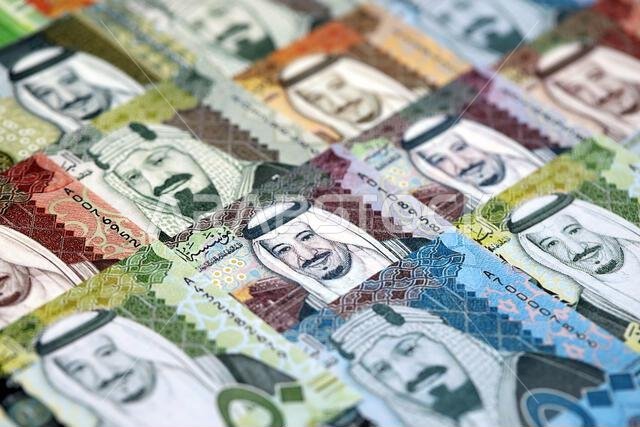 Saudi Arabia riyal money bills banknotes lies in big pile on table close up. Concept of finances and business in Saudi Arabia