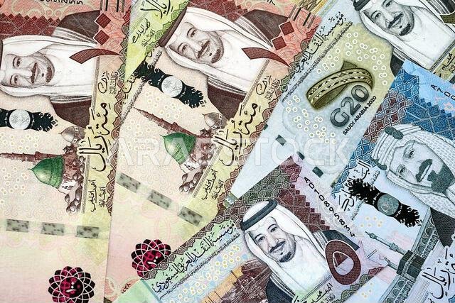 أوراق نقدية من الريال السعودي مكدسة في كومة كبيرة على طاولة، صورة مقرّبة. مفهوم التمويل والأعمال في المملكة العربية السعودية
