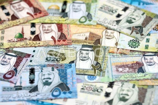 Saudi Arabia riyal money bills banknotes lies in big pile on table close up. Concept of finances and business in Saudi Arabia