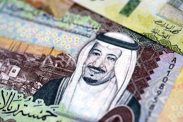 Saudi Arabia riyal money bills banknotes lies in big pile on table close up. Concept of finances and business in Saudi Arabia