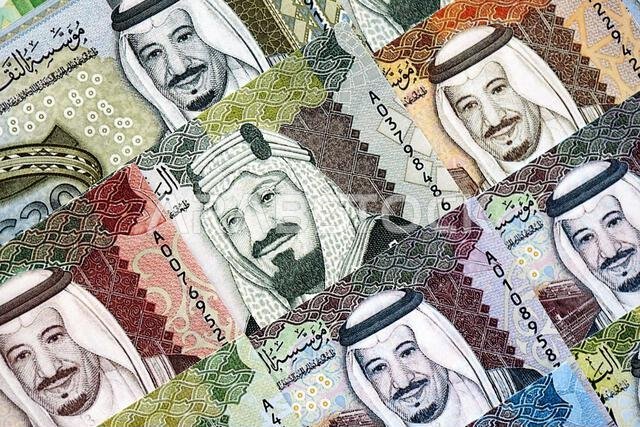 أوراق نقدية من الريال السعودي مكدسة في كومة كبيرة على طاولة، صورة مقرّبة. مفهوم التمويل والأعمال في المملكة العربية السعودية