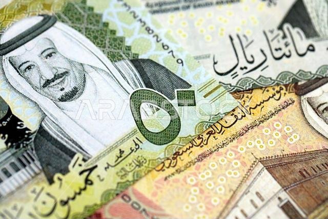 Saudi Arabia riyal money bills banknotes lies in big pile on table close up. Concept of finances and business in Saudi Arabia