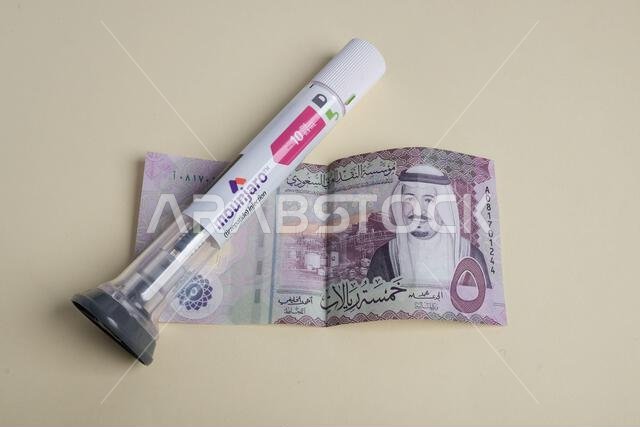 A tube of glue placed on top of a folded banknote featuring a portrait and intricate designs A tube of glue placed on top of a folded banknote featuring a portrait and intricate designs