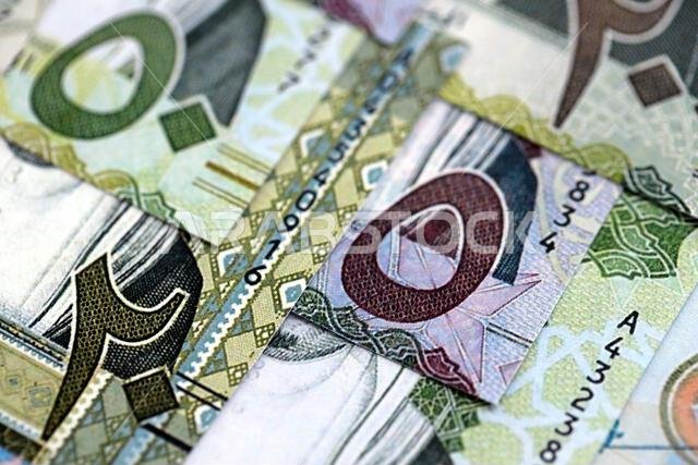 أوراق نقدية من الريال السعودي مكدسة في كومة كبيرة على طاولة، صورة مقرّبة. مفهوم التمويل والأعمال في المملكة العربية السعودية