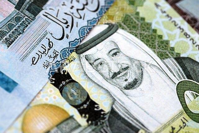 Saudi Arabia riyal money bills banknotes lies in big pile on table close up. Concept of finances and business in Saudi Arabia
