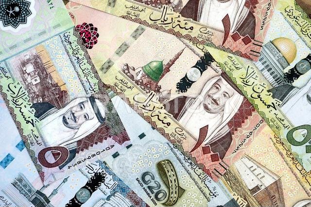 Saudi Arabia riyal money bills banknotes lies in big pile on table close up. Concept of finances and business in Saudi Arabia