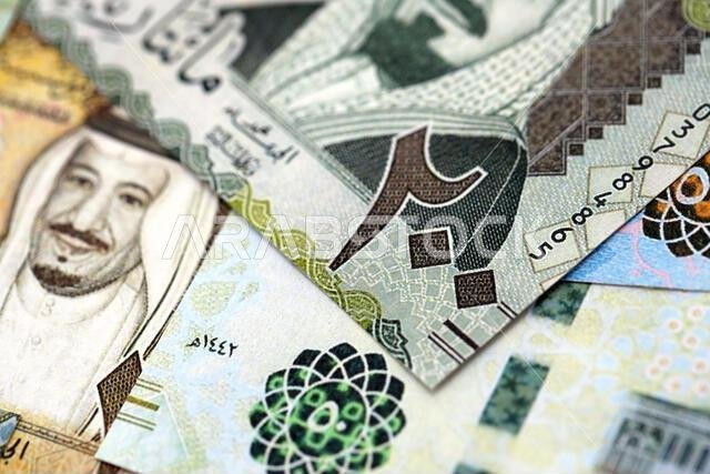 Saudi Arabia riyal money bills banknotes lies in big pile on table close up. Concept of finances and business in Saudi Arabia Saudi Arabia riyal money bills banknotes lies in big pile on table close up. Concept of finances and business in Saudi Arabia