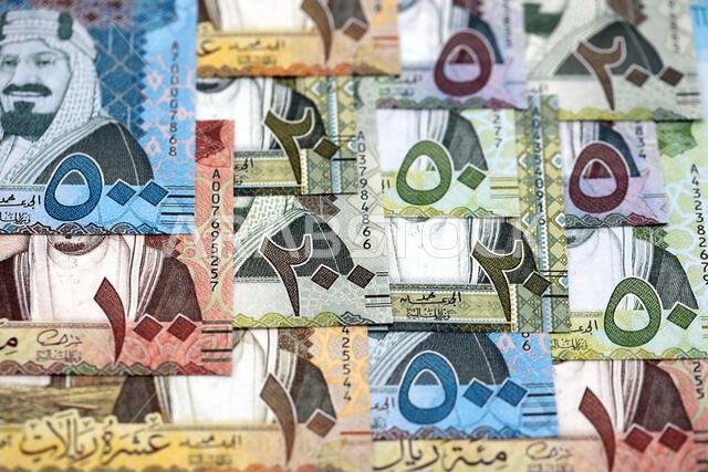 أوراق نقدية من الريال السعودي مكدسة في كومة كبيرة على طاولة، صورة مقرّبة. مفهوم التمويل والأعمال في المملكة العربية السعودية