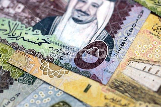 Saudi Arabia riyal money bills banknotes lies in big pile on table close up. Concept of finances and business in Saudi Arabia