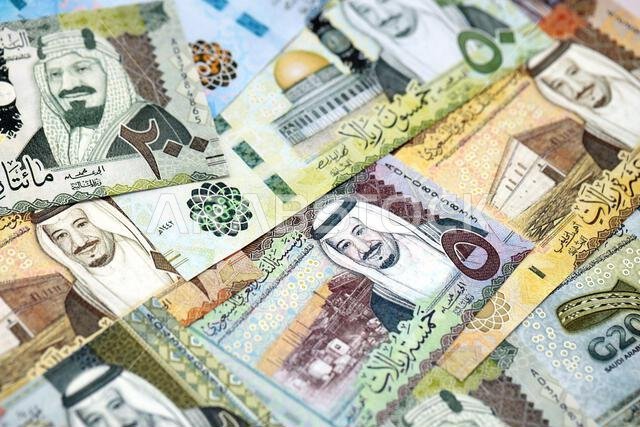 أوراق نقدية من الريال السعودي مكدسة في كومة كبيرة على طاولة، صورة مقرّبة. مفهوم التمويل والأعمال في المملكة العربية السعودية