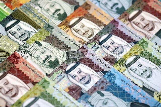 Saudi Arabia riyal money bills banknotes lies in big pile on table close up. Concept of finances and business in Saudi Arabia