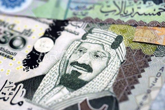 أوراق نقدية من الريال السعودي مكدسة في كومة كبيرة على طاولة، صورة مقرّبة. مفهوم التمويل والأعمال في المملكة العربية السعودية