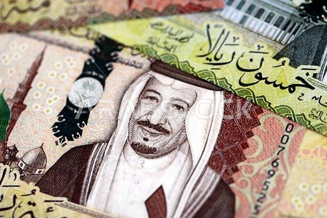 أوراق نقدية من الريال السعودي مكدسة في كومة كبيرة على طاولة، صورة مقرّبة. مفهوم التمويل والأعمال في المملكة العربية السعودية