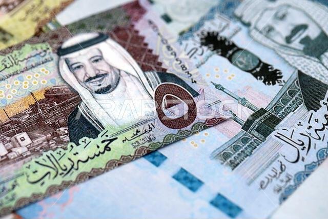 Saudi Arabia riyal money bills banknotes lies in big pile on table close up. Concept of finances and business in Saudi Arabia