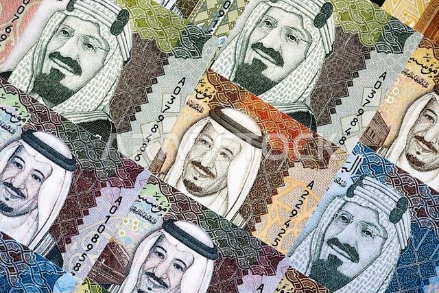 Saudi Arabia riyal money bills banknotes lies in big pile on table close up. Concept of finances and business in Saudi Arabia
