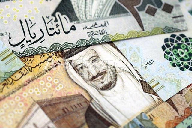 Saudi Arabia riyal money bills banknotes lies in big pile on table close up. Concept of finances and business in Saudi Arabia