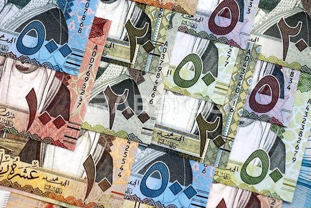 Saudi Arabia riyal money bills banknotes lies in big pile on table close up. Concept of finances and business in Saudi Arabia