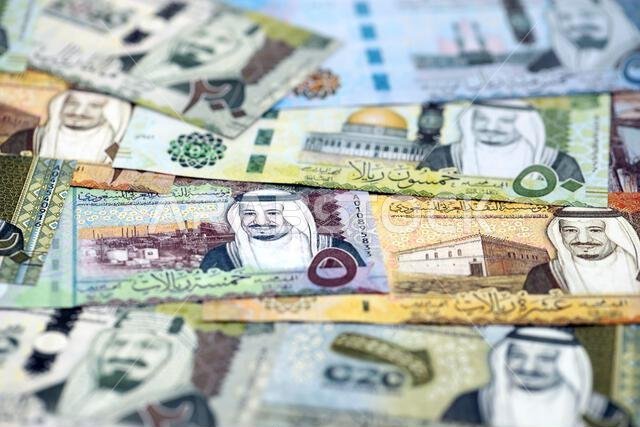 Saudi Arabia riyal money bills banknotes lies in big pile on table close up. Concept of finances and business in Saudi Arabia
