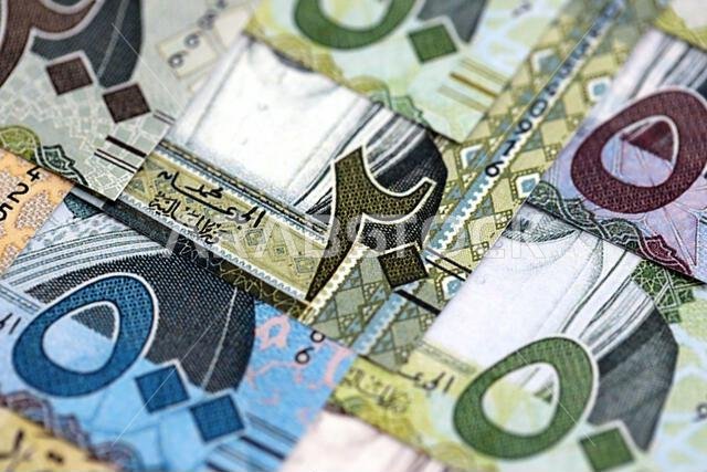 Saudi Arabia riyal money bills banknotes lies in big pile on table close up. Concept of finances and business in Saudi Arabia