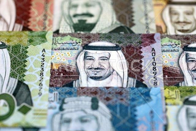 أوراق نقدية من الريال السعودي مكدسة في كومة كبيرة على طاولة، صورة مقرّبة. مفهوم التمويل والأعمال في المملكة العربية السعودية