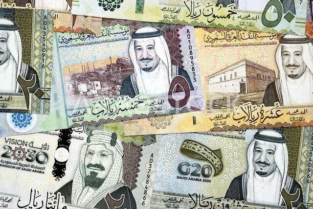 Saudi Arabia riyal money bills banknotes lies in big pile on table close up. Concept of finances and business in Saudi Arabia