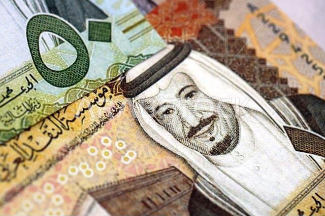 أوراق نقدية من الريال السعودي مكدسة في كومة كبيرة على طاولة، صورة مقرّبة. مفهوم التمويل والأعمال في المملكة العربية السعودية