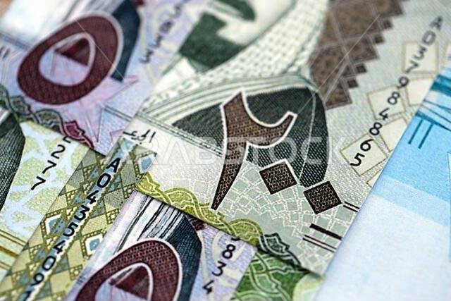 Saudi Arabia riyal money bills banknotes lies in big pile on table close up. Concept of finances and business in Saudi Arabia