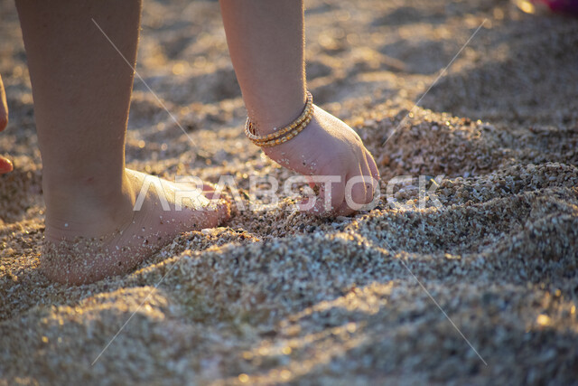 صورة ابداعية ليد طفلة تمسك برمال البحر على شاطئ البحر في المملكة العربية السعودية، اللعب بالرمال، رمال البحر، انشطة ترفيهية على شاطئ البحر، السياحة في السعودية