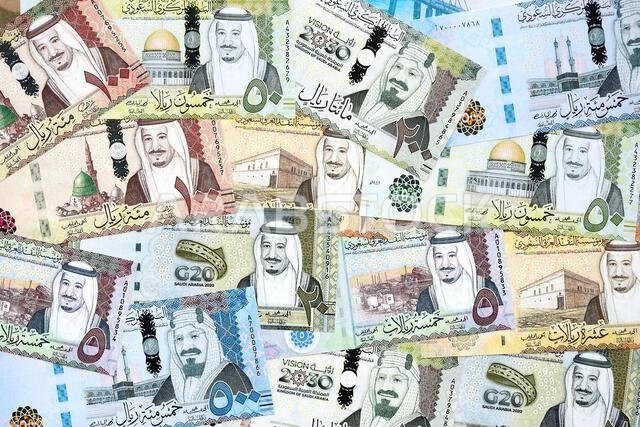 أوراق نقدية من الريال السعودي مكدسة في كومة كبيرة على طاولة، صورة مقرّبة. مفهوم التمويل والأعمال في المملكة العربية السعودية