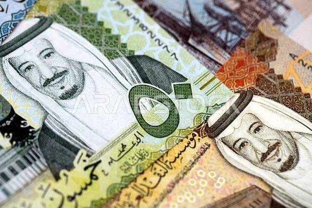 أوراق نقدية من الريال السعودي مكدسة في كومة كبيرة على طاولة، صورة مقرّبة. مفهوم التمويل والأعمال في المملكة العربية السعودية