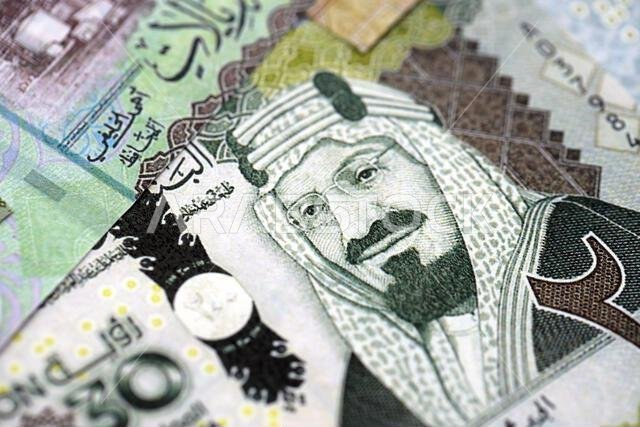 Saudi Arabia riyal money bills banknotes lies in big pile on table close up. Concept of finances and business in Saudi Arabia