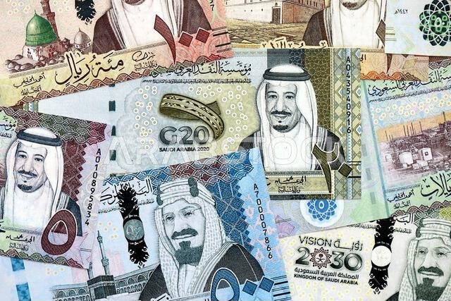 Saudi Arabia riyal money bills banknotes lies in big pile on table close up. Concept of finances and business in Saudi Arabia