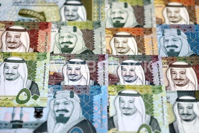 Saudi Arabia riyal money bills banknotes lies in big pile on table close up. Concept of finances and business in Saudi Arabia