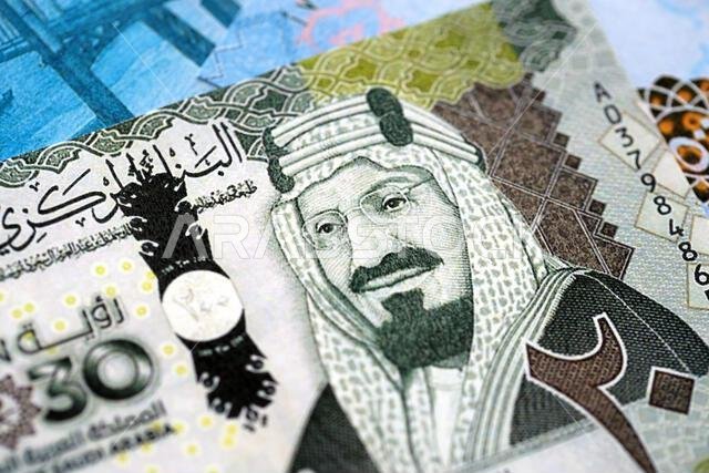 Saudi Arabia riyal money bills banknotes lies in big pile on table close up. Concept of finances and business in Saudi Arabia