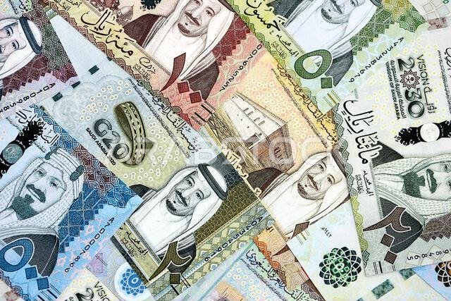 أوراق نقدية من الريال السعودي مكدسة في كومة كبيرة على طاولة، صورة مقرّبة. مفهوم التمويل والأعمال في المملكة العربية السعودية