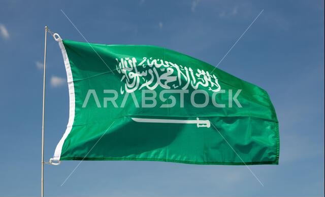 Flag of Saudi Arabia fluttering on flagpole against blue sky