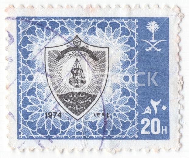 المملكة العربية السعودية - 26 نوفمبر 1986: طابع بريدي من فئة 20 هلالة، باللونين الأزرق الداكن والأسود، يحمل الشعار الرسمي لجامعة الإمام محمد بن سعود الإسلامية بالمدينة المنورة. يأخذ الشعار شكل درع، ويتوسطه صورة لمصباح زيتي مزخرف (رمز تقليدي للمعرفة والتنوير) تشع منه أشعة. يُحيط بهذا الدرع نقش هندسي إسلامي دقيق من النجوم المتشابكة، يغطي خلفية الطابع الرئيسية. إلى يمين النقش المركزي