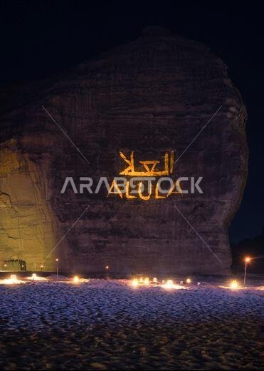 جبل الفيل - صخرة الفيل في المساء، منظر طبيعي مضاء، نص العلية وترجمتها العربية معروضة على جدار حجري، مقاعد للناس موضوعة على جبل الفيل - صخرة الفيل في المساء، منظر طبيعي مضاء، نص العلية وترجمتها العربية معروضة على جدار حجري، مقاعد للناس موضوعة على