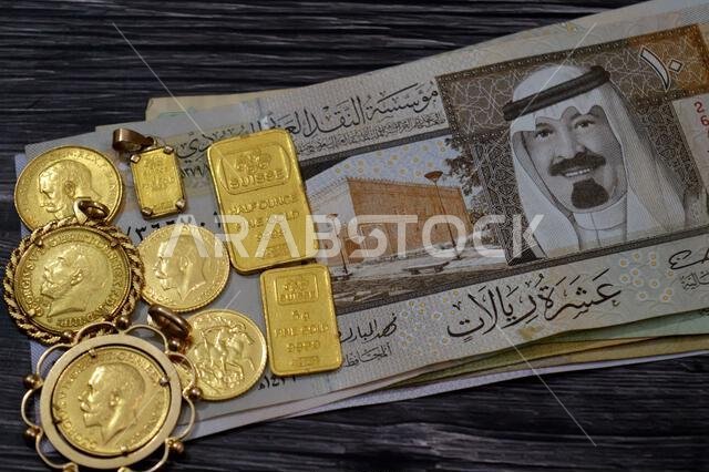 Cairo, Egypt, January 9 2026: Saudi Arabian riyals money banknotes SAR and Pamp Suisse gold bars and The sovereign is a British gold coins, for invest