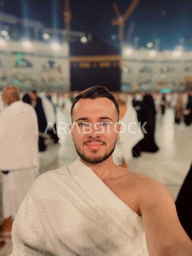 Muslim Man in Ihram Taking a Selfie Photo at Kaaba in Mecca During Hajj Pilgrimage Islamic Religious Tradition and Spirituality Saudi Arabia.