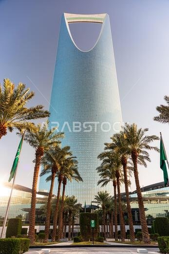 الرياض، المملكة العربية السعودية - 1 يناير 2026: ناطحة سحاب زجاجية شاهقة، مركز المملكة، في الرياض، ذات قمة مقوسة مميزة، تقف وسط أشجار النخيل و