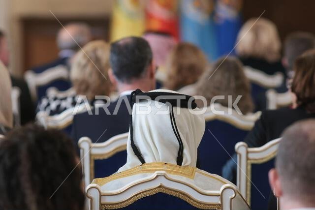 تفاصيل ذات عمق مجال ضحل مع رجل في الجمهور يرتدي غترة إسلامية، شماغ، كوفية، وهو وشاح قطني مربع مثبت بحبل أسود يسمى