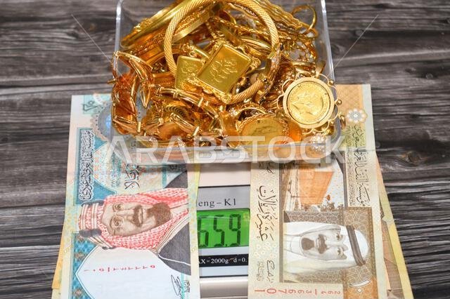 القاهرة، مصر، 9 يناير 2026: ريال سعودي، وكومة من الذهب على ميزان رقمي بالجرام، وسبائك ذهبية، وعملات ذهبية، وأساور.