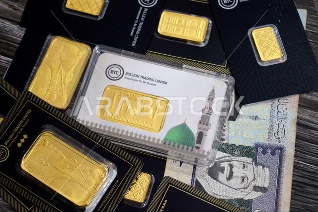 القاهرة، مصر، 6 فبراير 2026: ريال سعودي وسبائك ذهب أصفر عيار 24 قيراطًا في مركز تداول سبائك البيتكوين. المسجد النبوي في المتوسط.