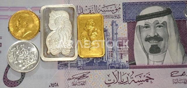 A fragment of Saudi Arabian riyal money SAR and 24K gold and pure fine silver bars and sovereign coins, for investment or savings, gold and silver wit