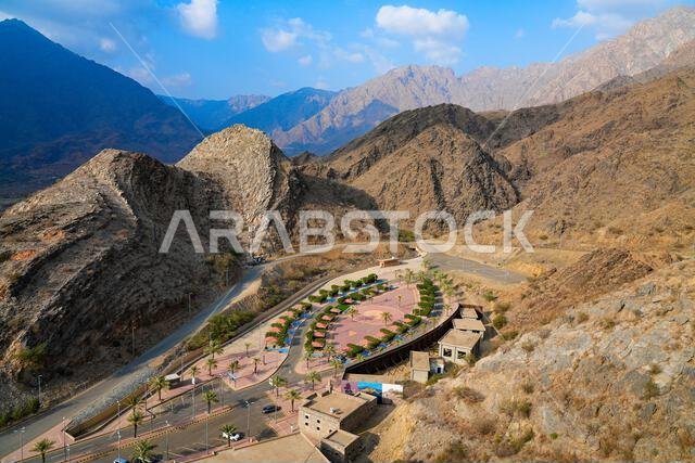Aerial view of the visitor park of Thee Ain Heritage Village against a desert mountain backdrop in Saudi Arabia