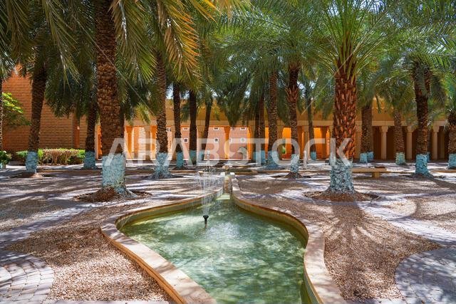 نافورة مياه تقليدية وبستان نخيل في قصر المربع التاريخي بالرياض، المملكة العربية السعودية